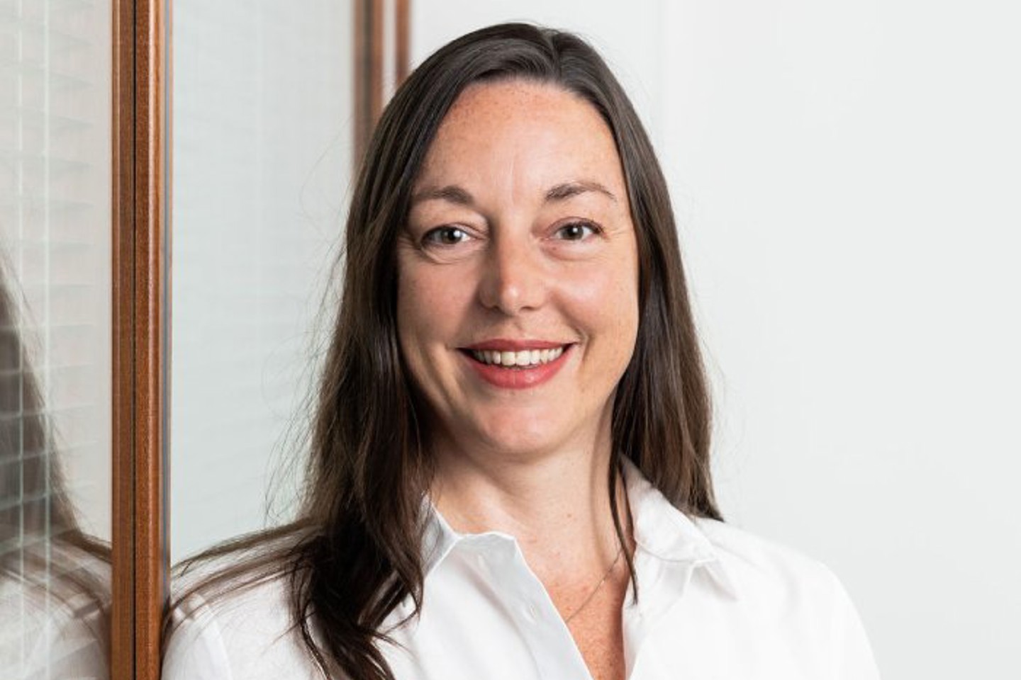 Professional woman wearing a white shirt, smiling confidently 